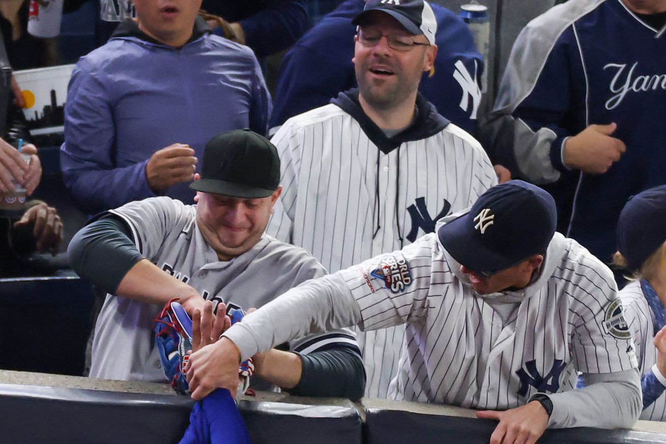 Mookie Betts, in his grey Dodgers’ jersey, finds his blue-sleeved arm held by a pair of fans, one of whom pries open his glove, causing the ball to fall to the turf. Showing remarkable restraint, Betts did not flip off said “fans” when returning to his position in right field.