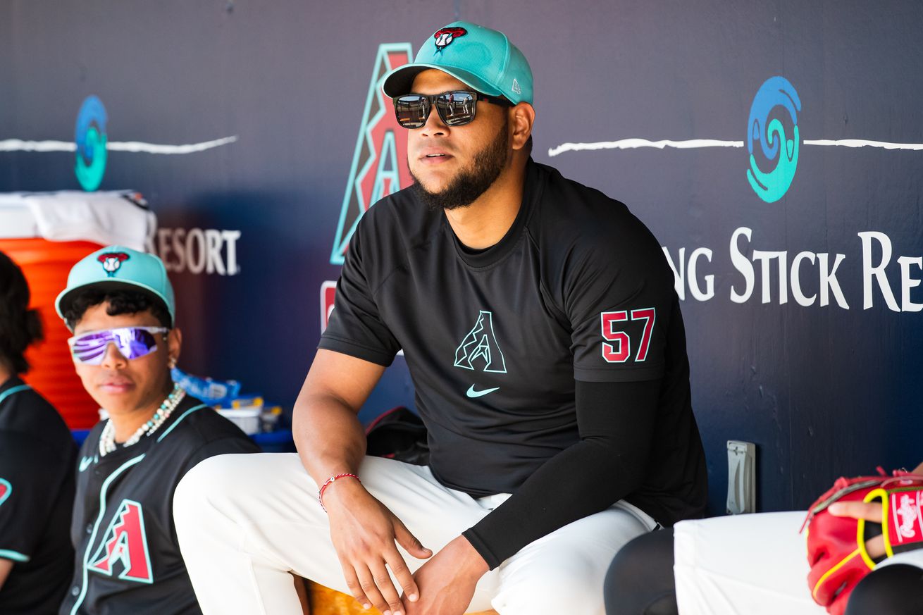 Eduardo Rodriguez sits on top of the bench in the dugout, out of uniform, looking on during a game, like he did so many times this season