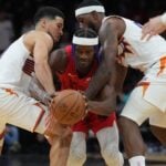 Dec 7, 2024; Miami, Florida, USA; Miami Heat forward Jimmy Butler (22) tries to drive between Phoenix Suns guard Devin Booker (left) and forward Royce O'Neale (right) during the second half at Kaseya Center.